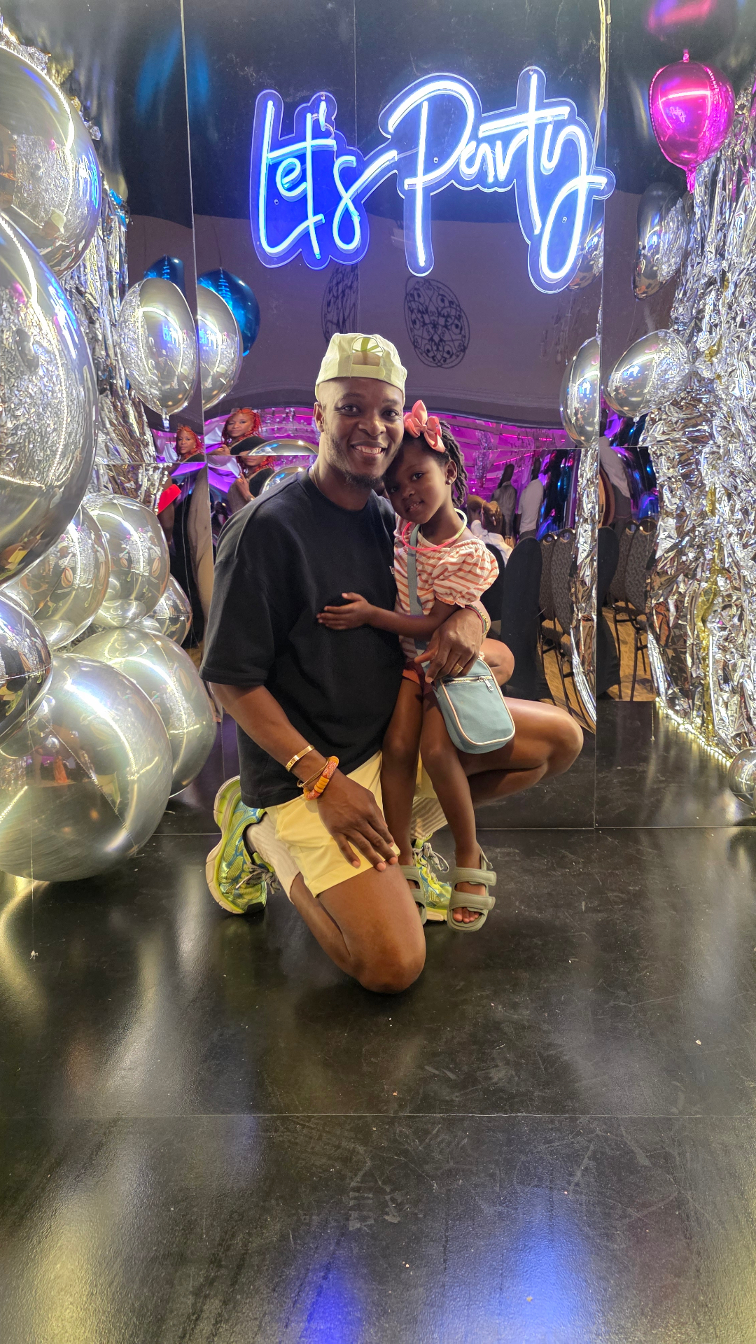 Father and daughter celebrating at a party with silver balloons and a neon sign